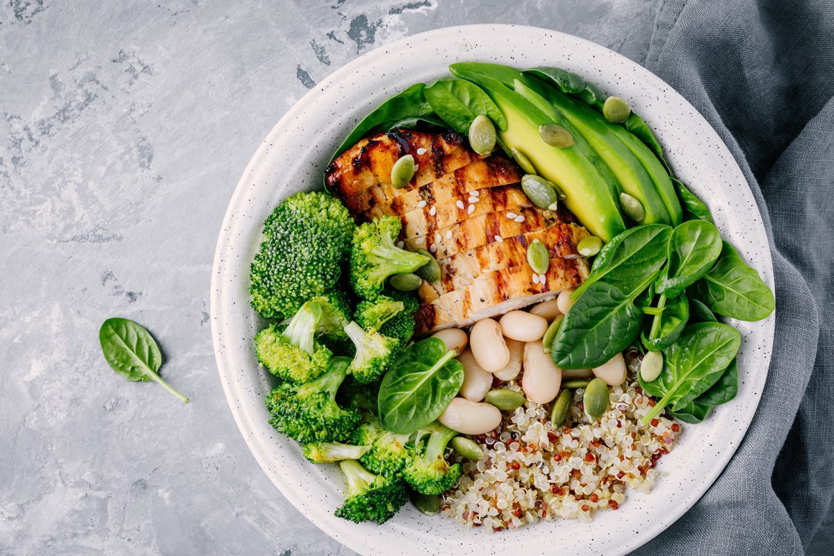 Quinoa healthy lunch bowl with chicken as protein avocado as fat and vegetables broccoli and spinach and beans