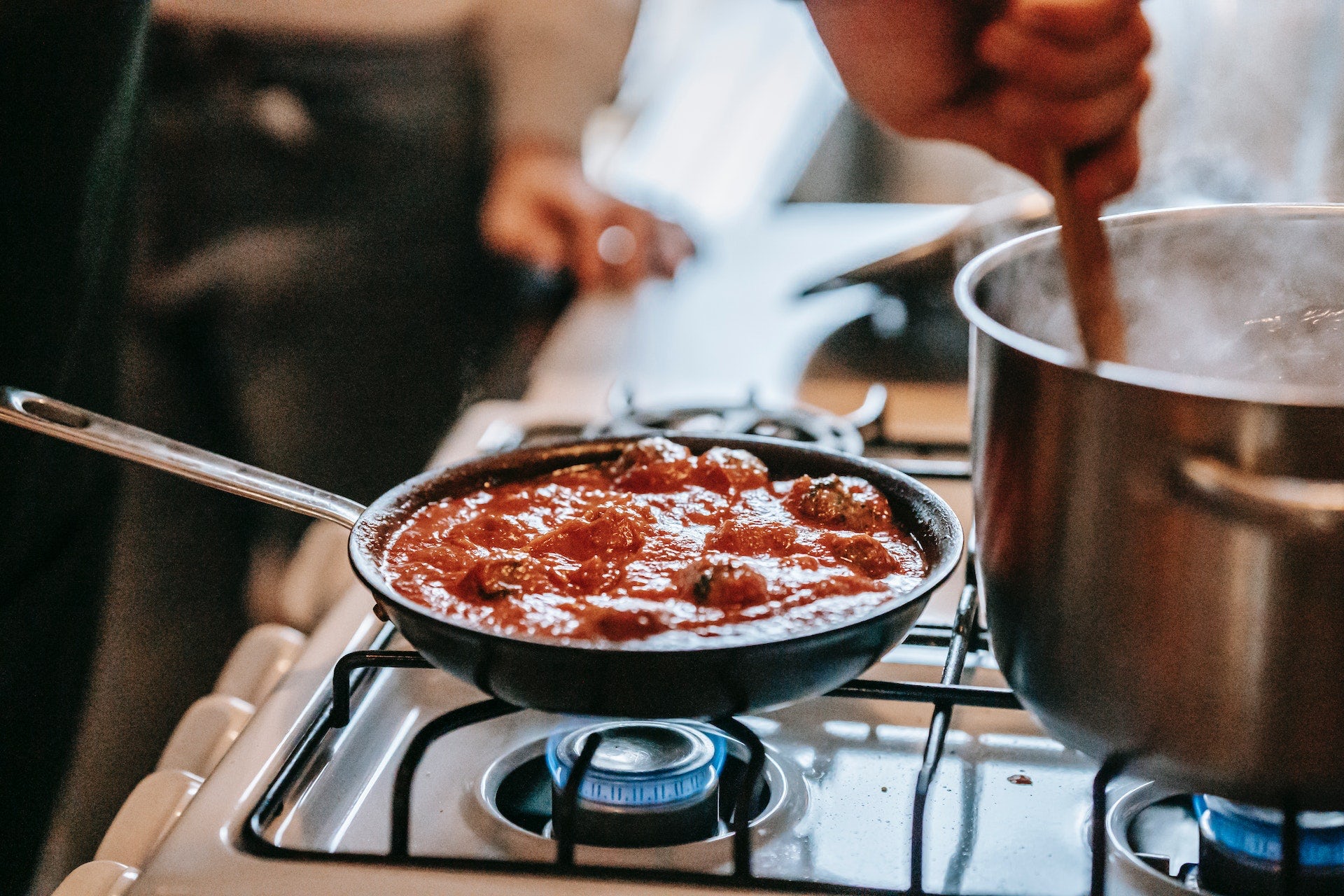 Tomato dish and saucepan of boiling water on gas stove