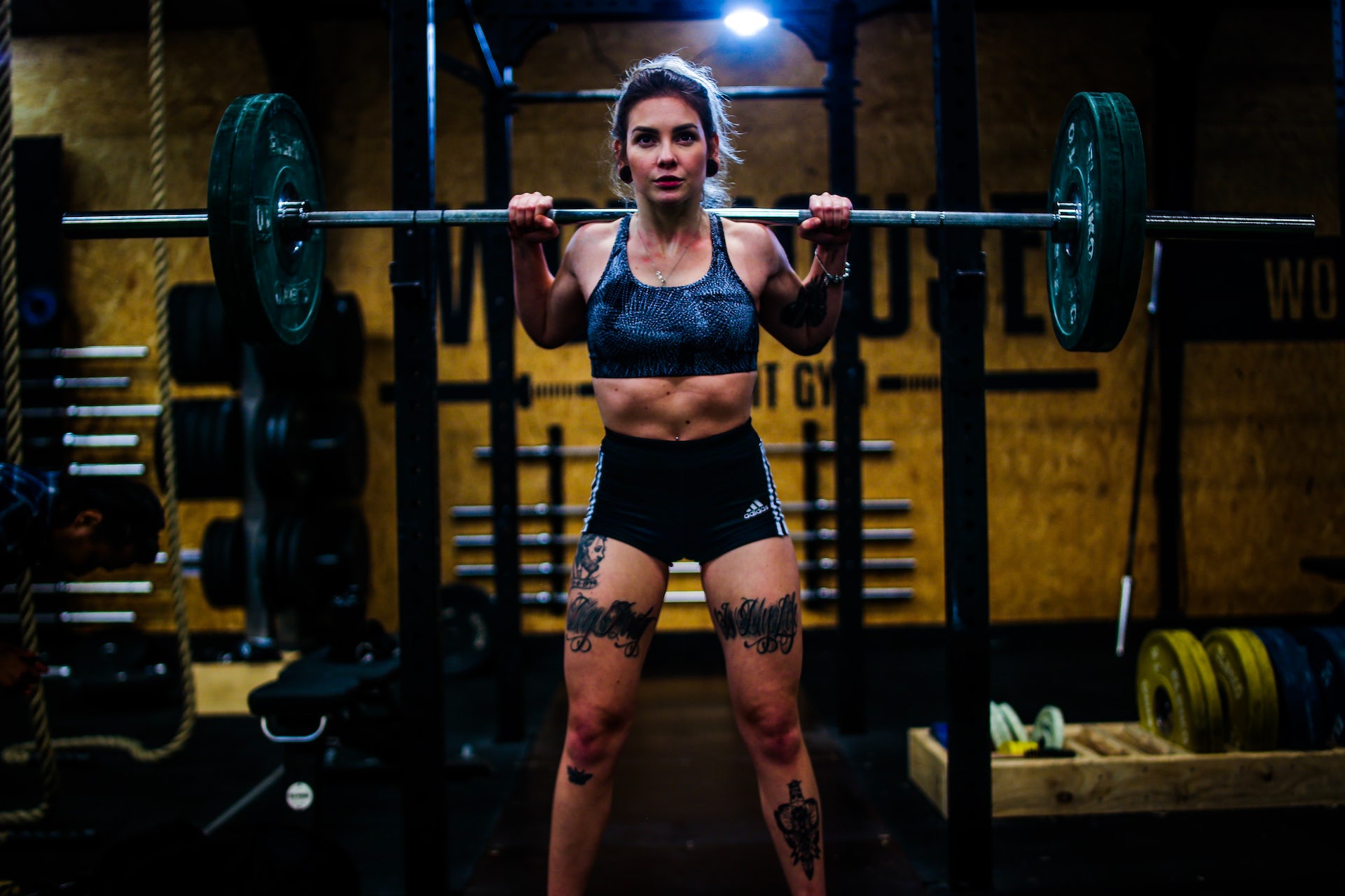 A woman prepares to squat with a heavy barbell.