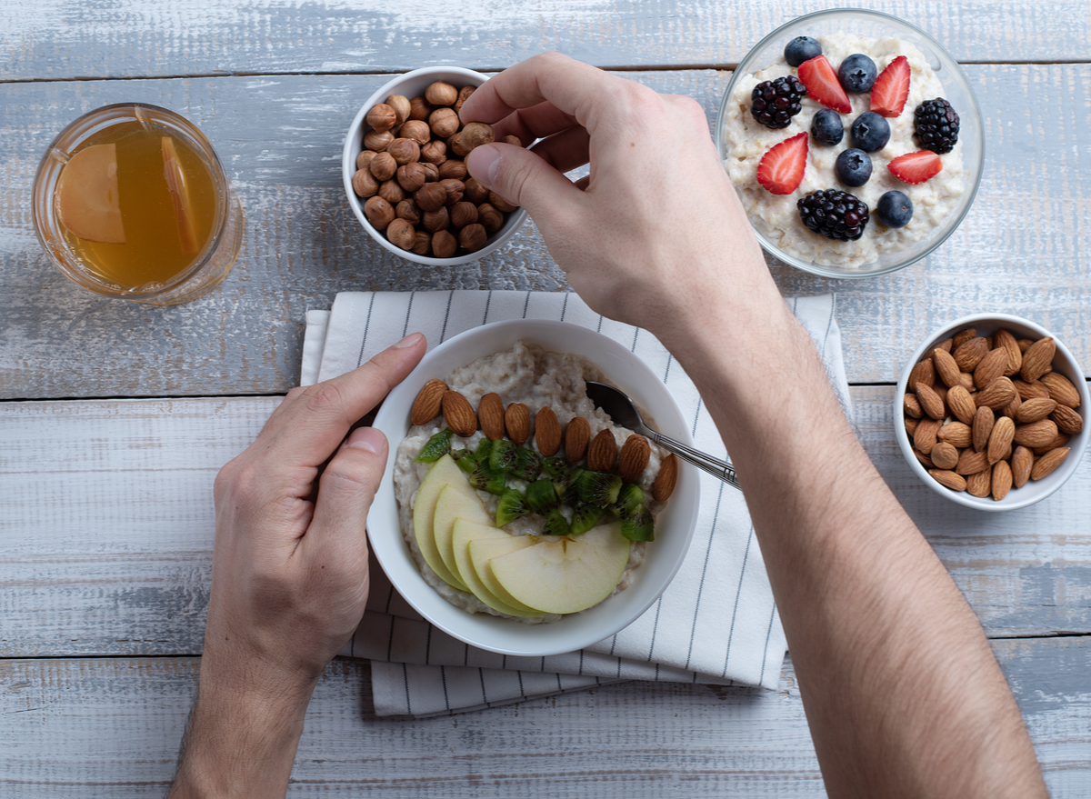 man preparing bowl of porridge with fruits and nuts