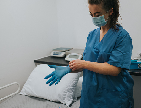 A health care working puts on blue latex gloves