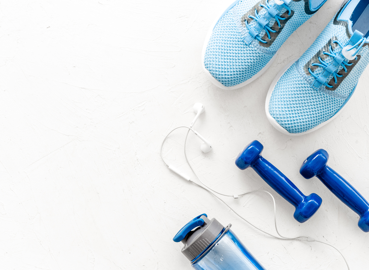 running shoes with weights and bottle of water, plain background