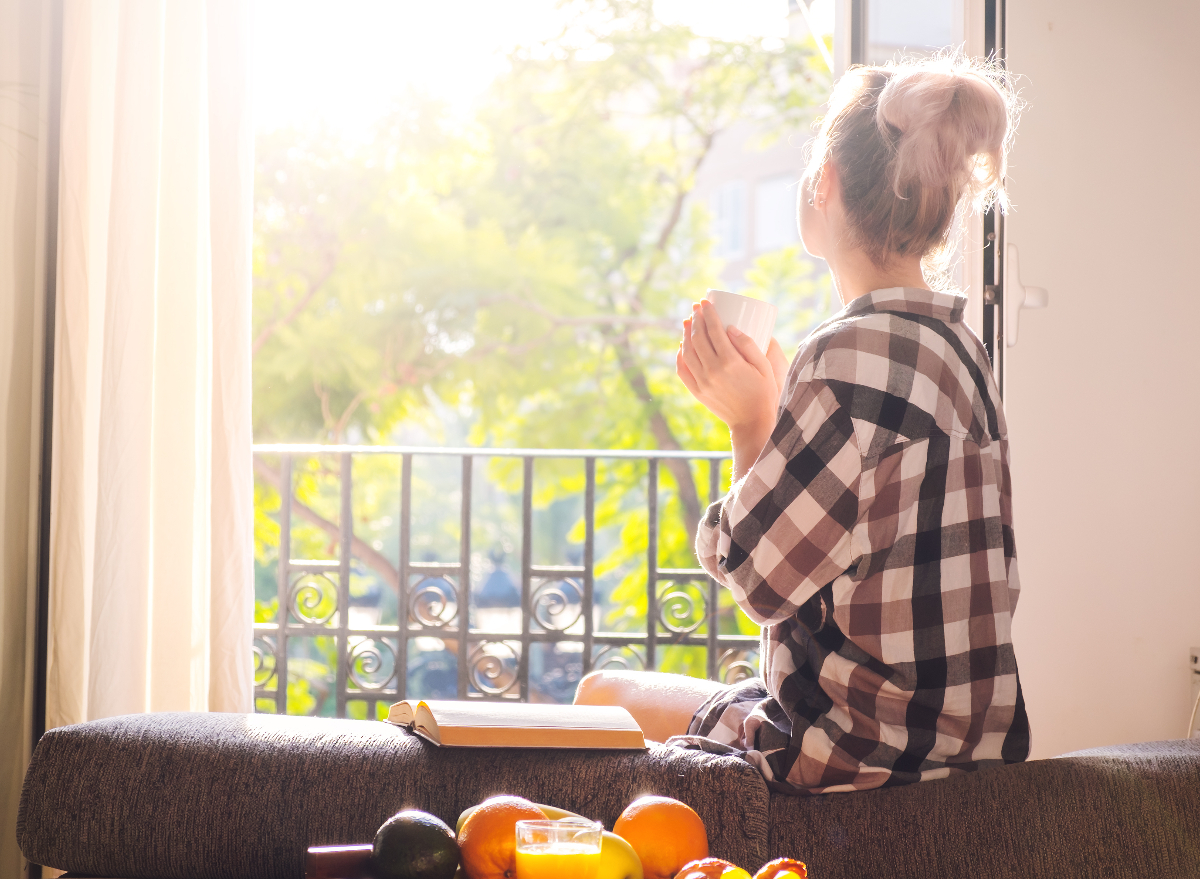 woman drinking morning coffee in bright room with sun streaming in