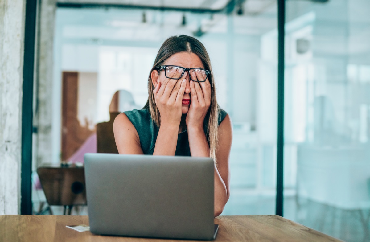 Stressed business woman rubbing her eyes in the office.