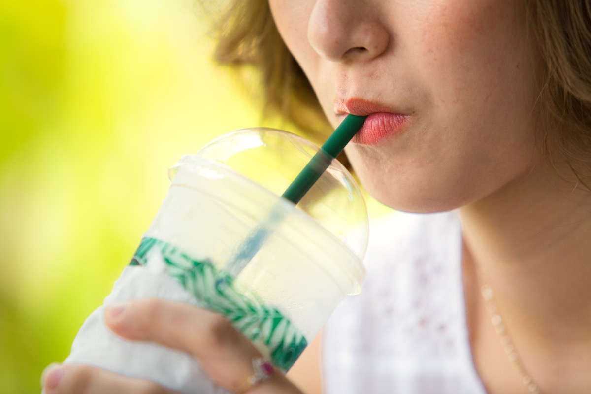 woman drinking iced coffee with straw