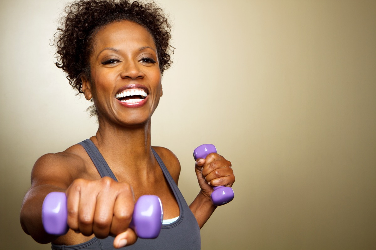 Happy fitness woman lifting weights smiling and energetic