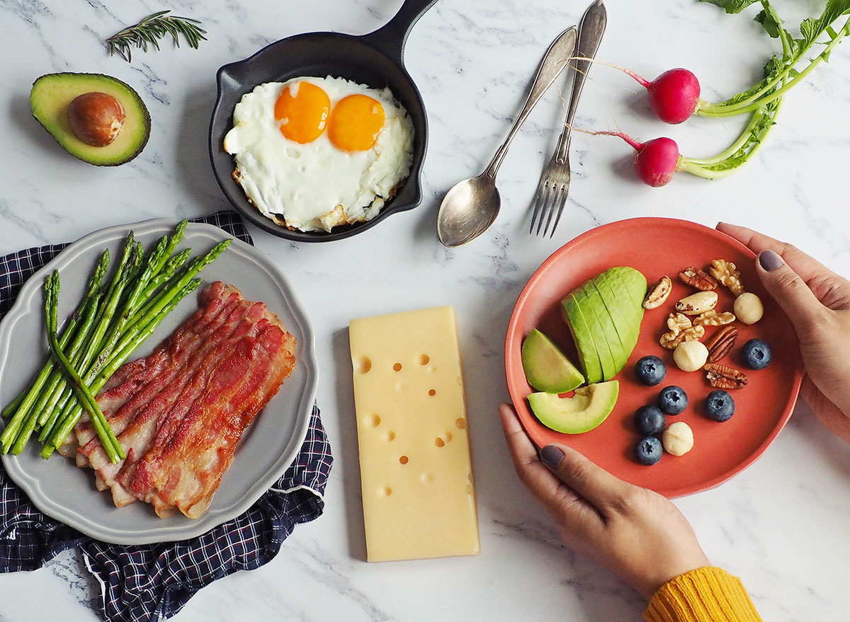 Woman holding a plate of ketogenic food at a table