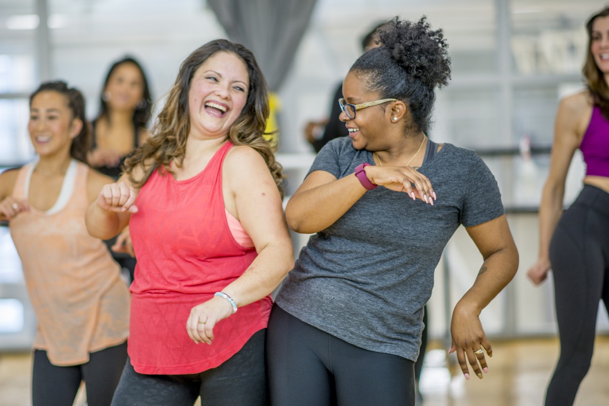 white woman and black woman dancing together in an exercise class