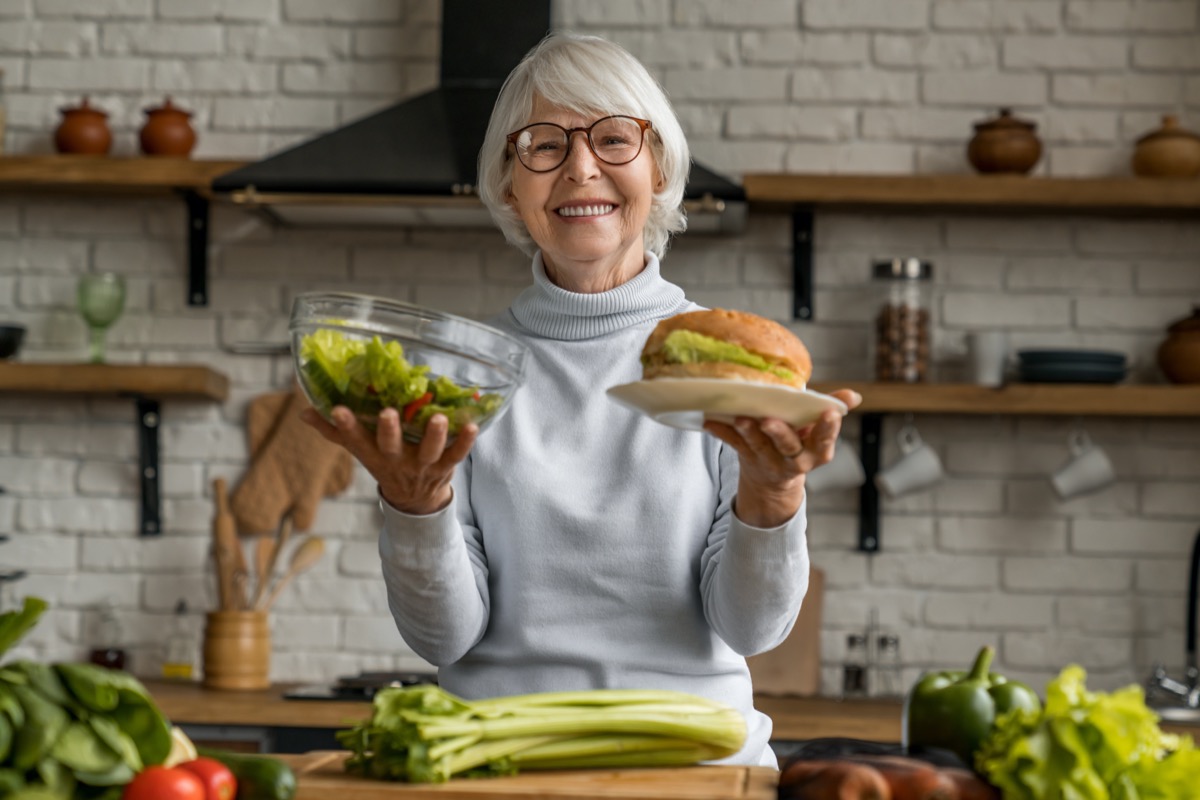 Senior woman choosing between healthy and junk food