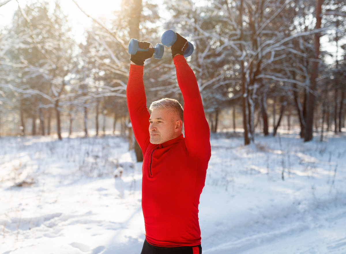 man exercising with dumbbells outdoors along winter walk