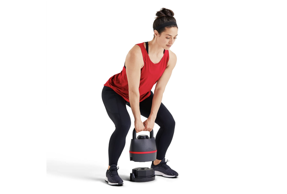 Squatting girl holding Bowflex kettlebell.