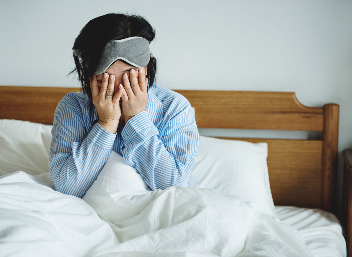 Woman waking up in bed but she is exhausted and sleep deprived