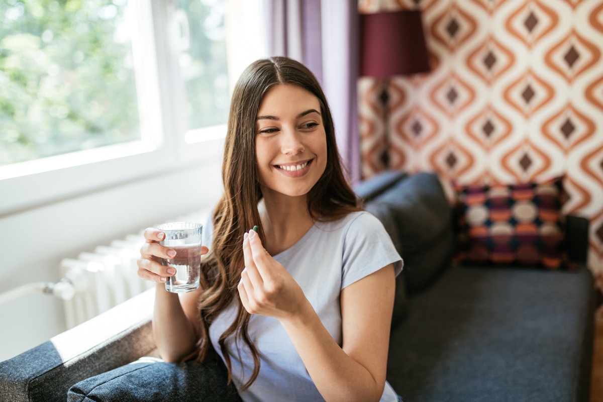 Smiling woman taking a pill.