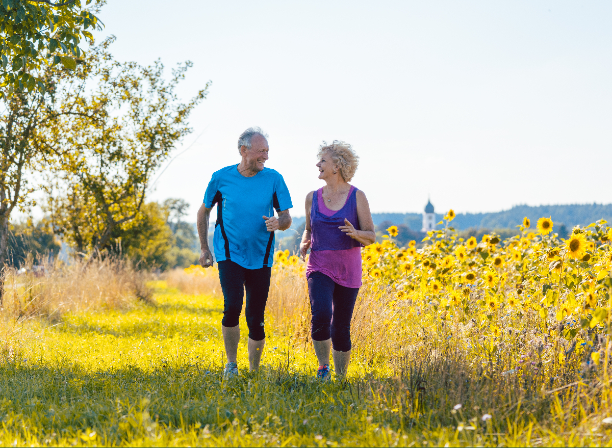 fitness mature couple running through sunny field