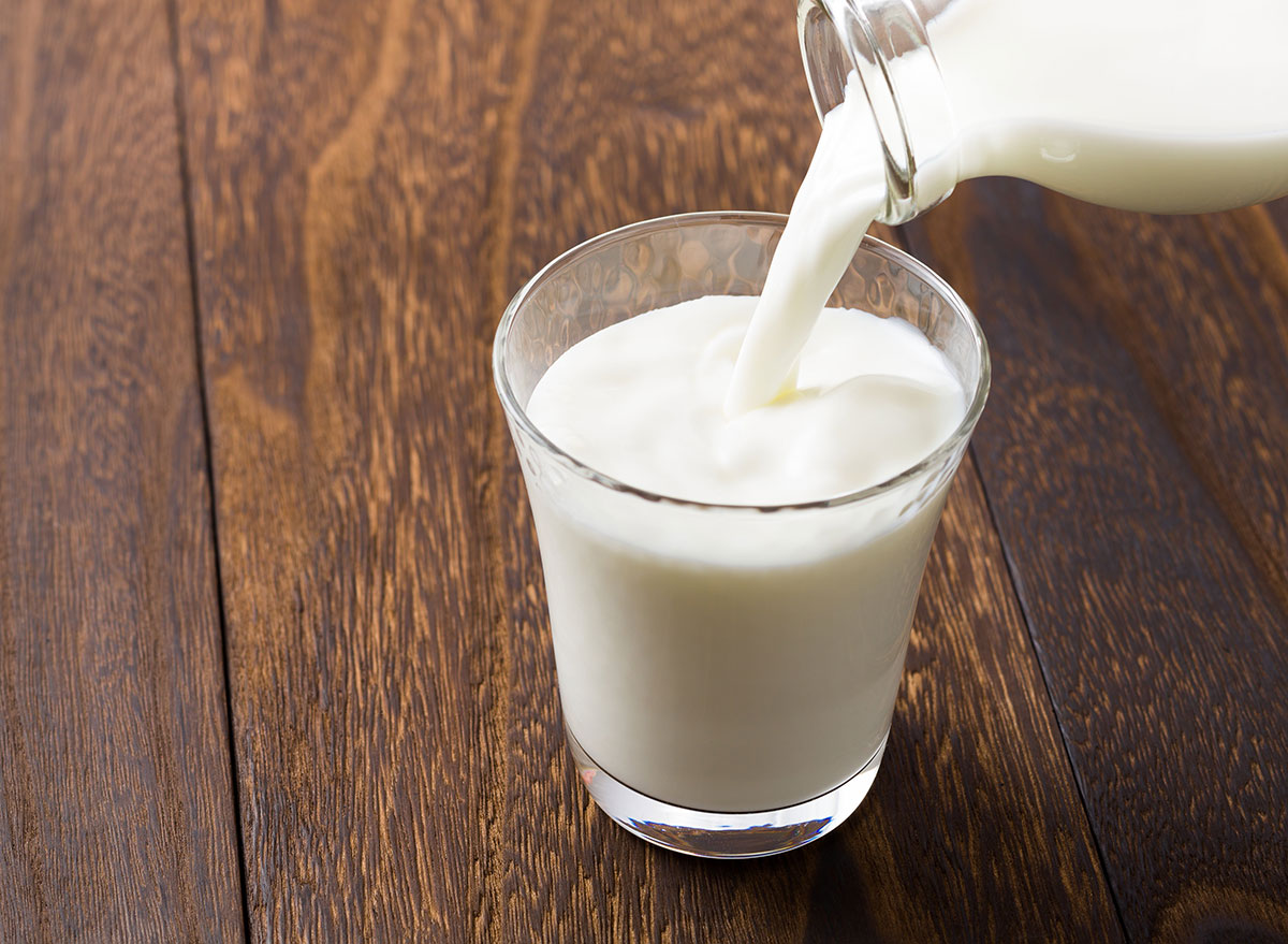 glass of milk being poured from a glass jar