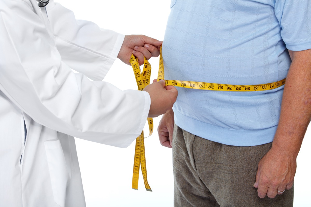 Doctor measuring waist body fat of obese man.