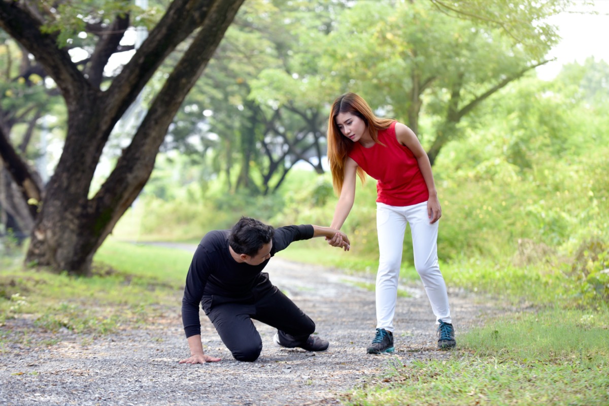 Woman helping an injured man on the running track in the garden