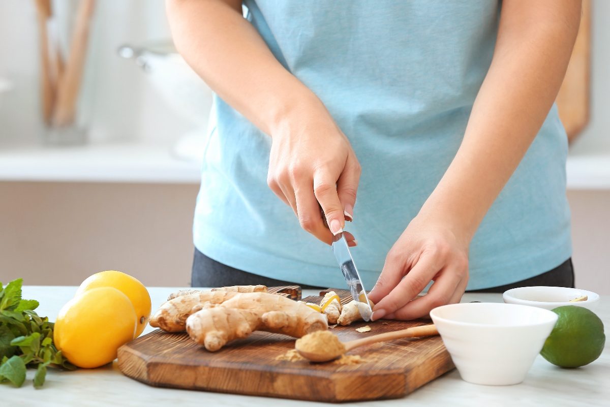 woman cutting ginger on a cutting board