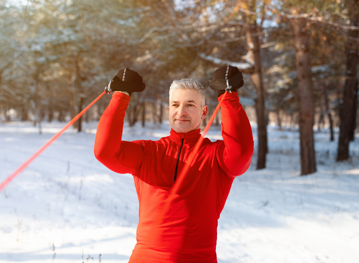 mature man in snow exercising with resistance band, demonstrates exercises not to skip after 50