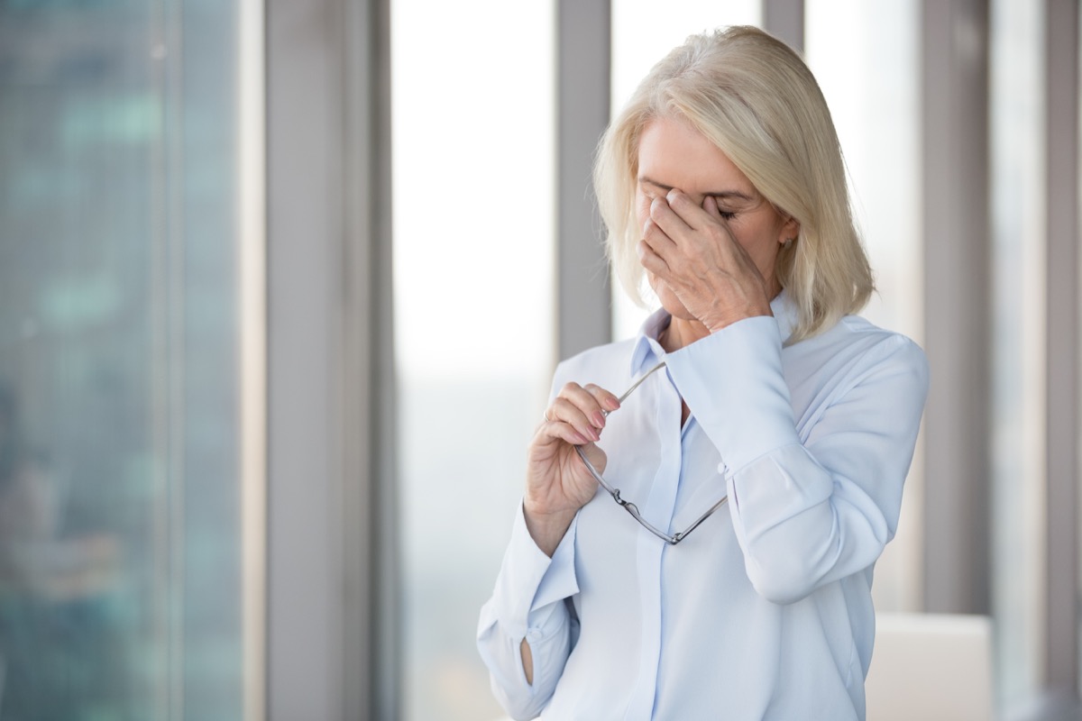 Tired mature woman taking off glasses suffering from headache