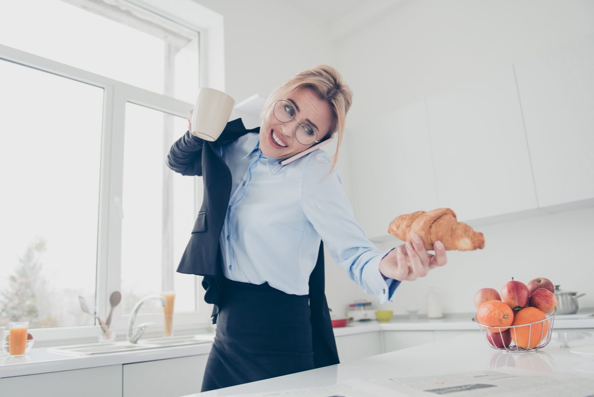 woman running, talking on the phone and holding a croissant