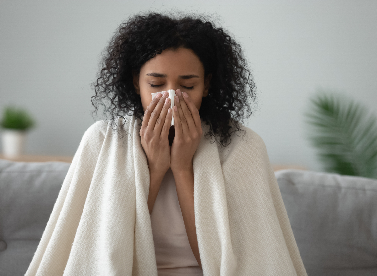 woman blowing her nose, sick at home in cold weather