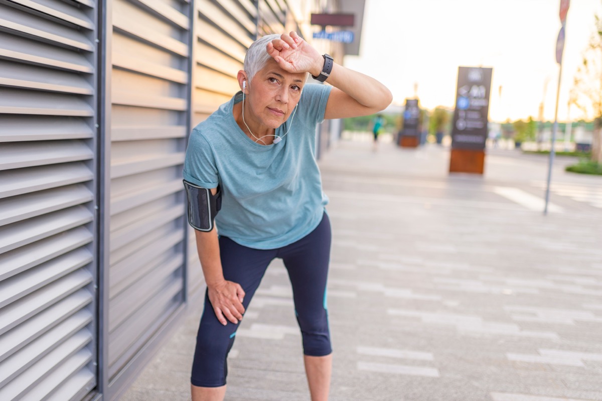 Portrait of athletic mature woman resting after jogging in the park during sunset