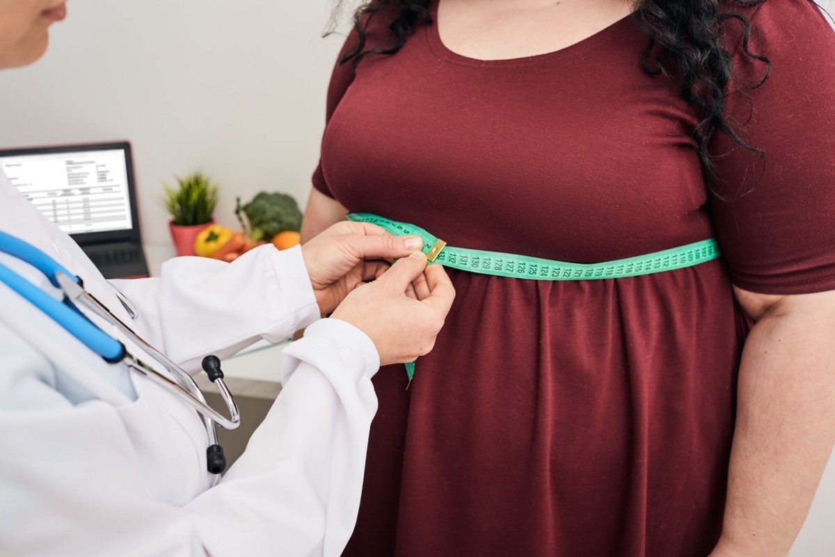 Nutritionist inspecting a woman's waist using a tape measure