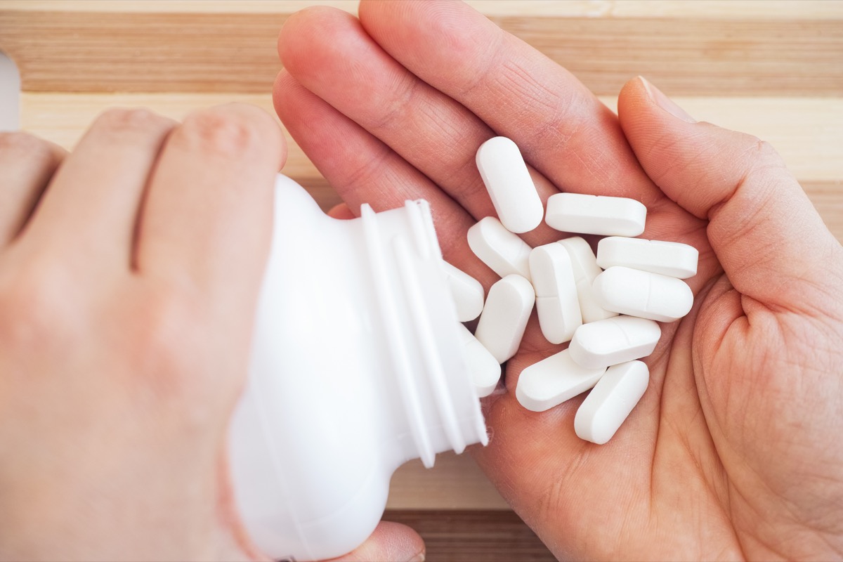 Woman taking magnesium pills from a bottle.  Close up.