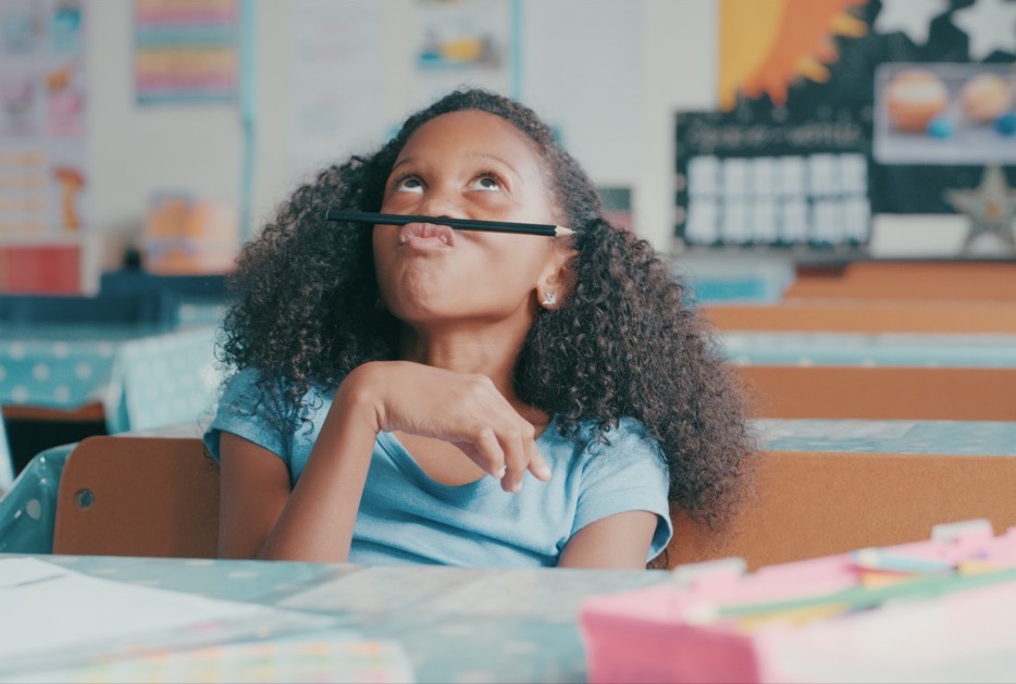 Young girl looking bored while playing on a desk.