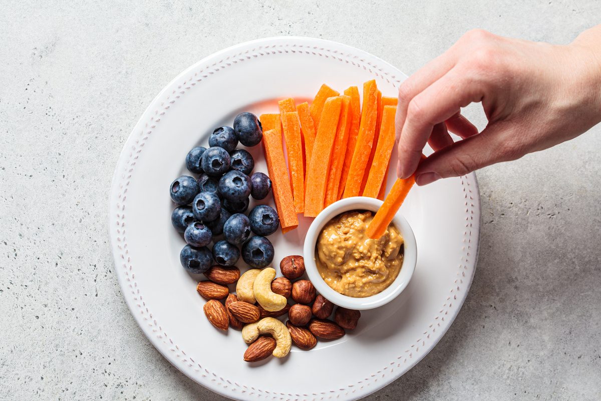 plate of sandwiches with carrots, peanut butter, nuts and blueberries