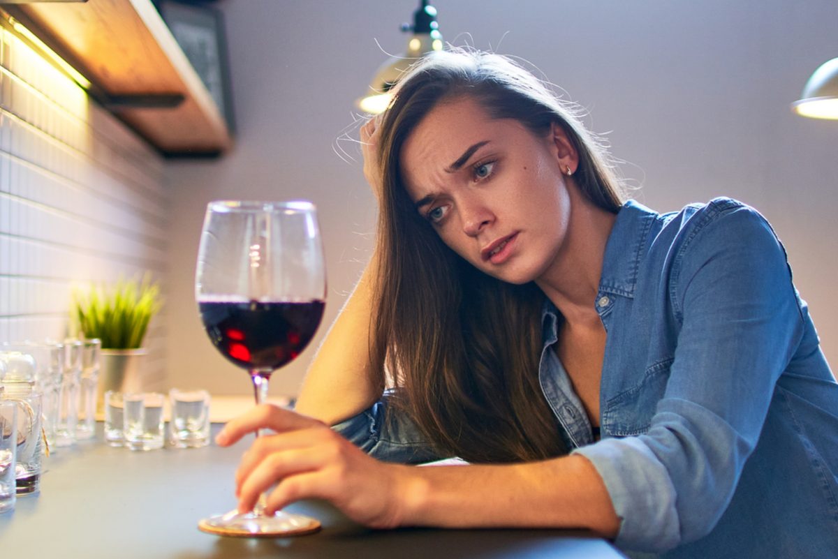 Sad woman drinking wine in the kitchen.