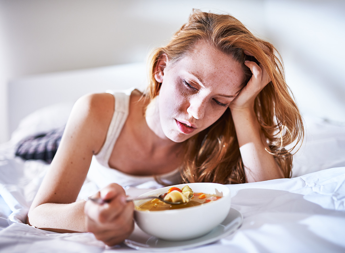 woman eating in bed while feeling sick