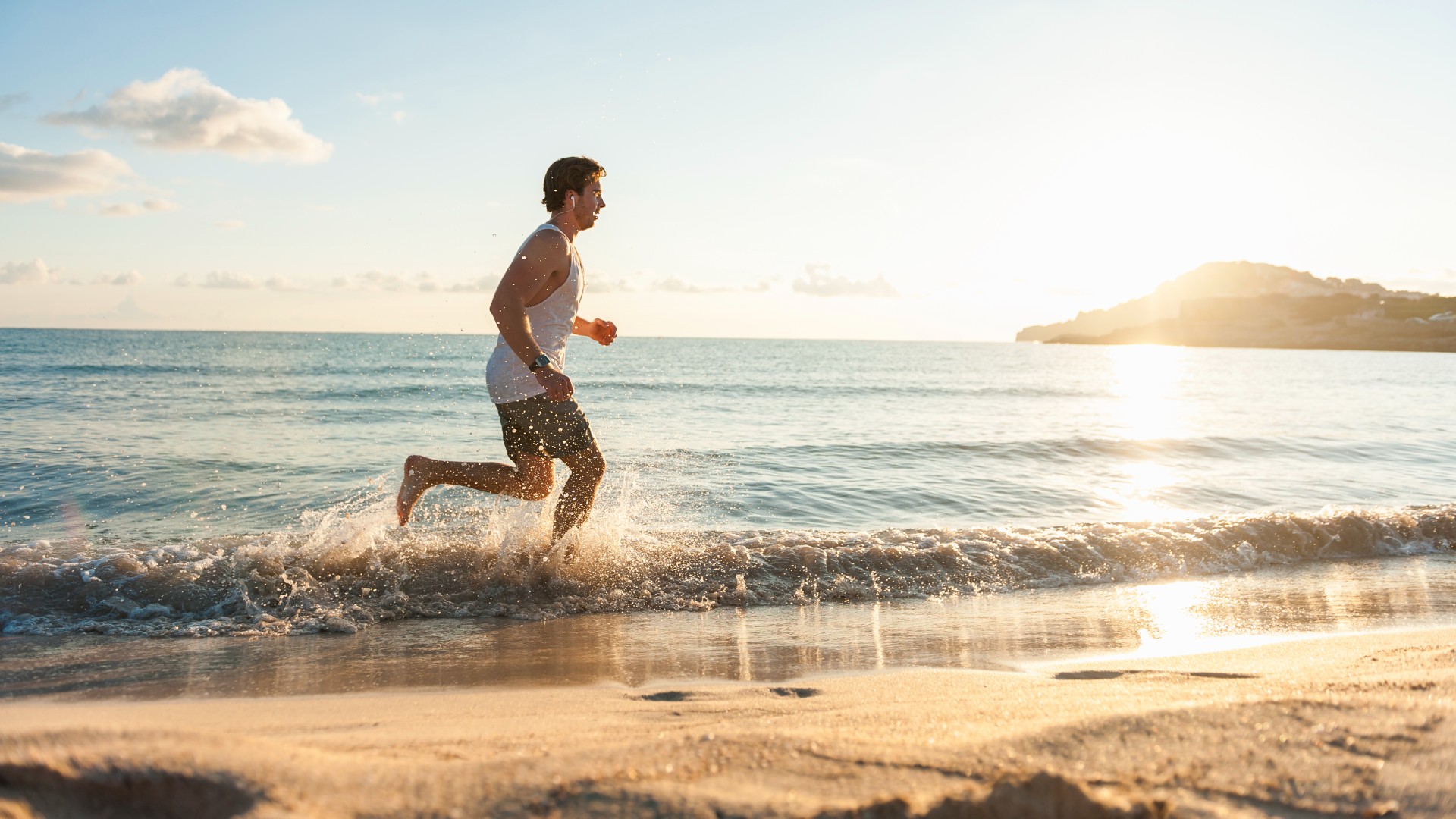 man running in the water on the beach