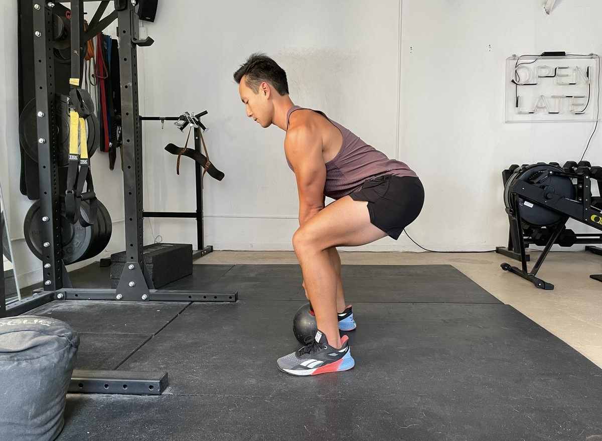 trainer demonstrating kettlebell deadlift to shrink his belly