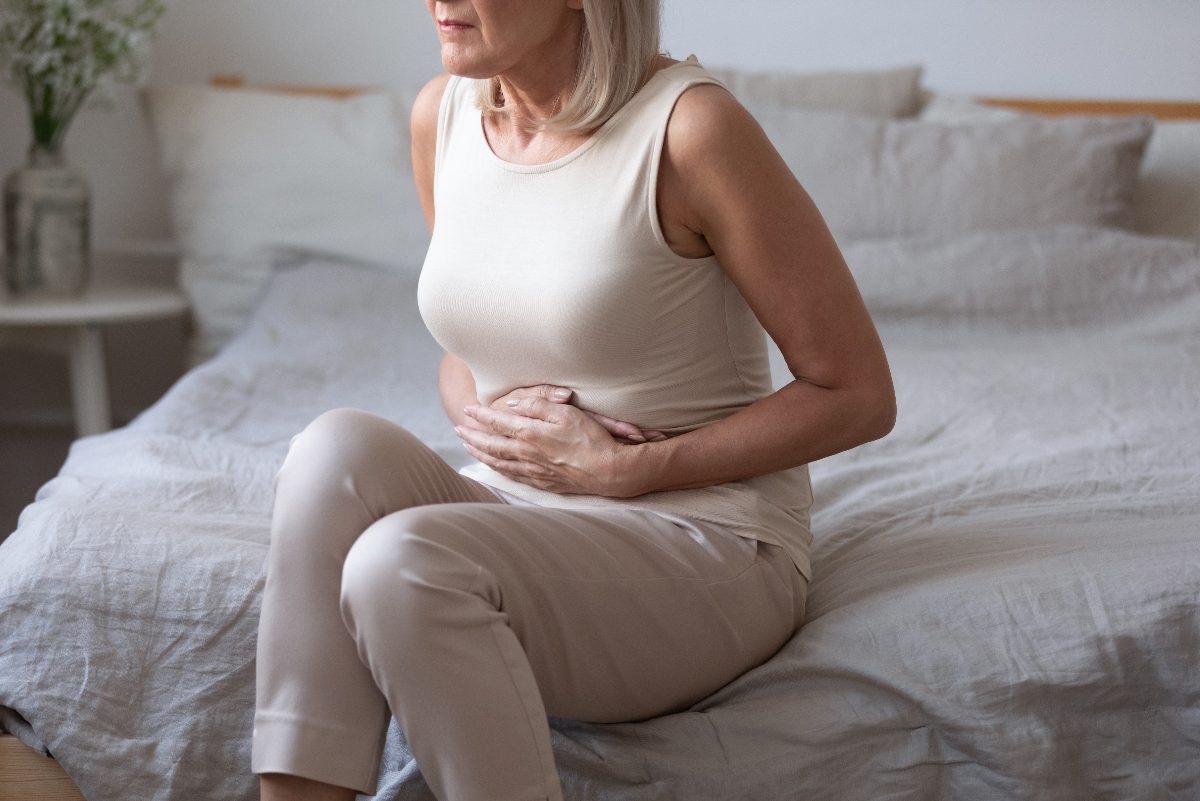 mature woman dealing with poor gut health, stomach ache in bed