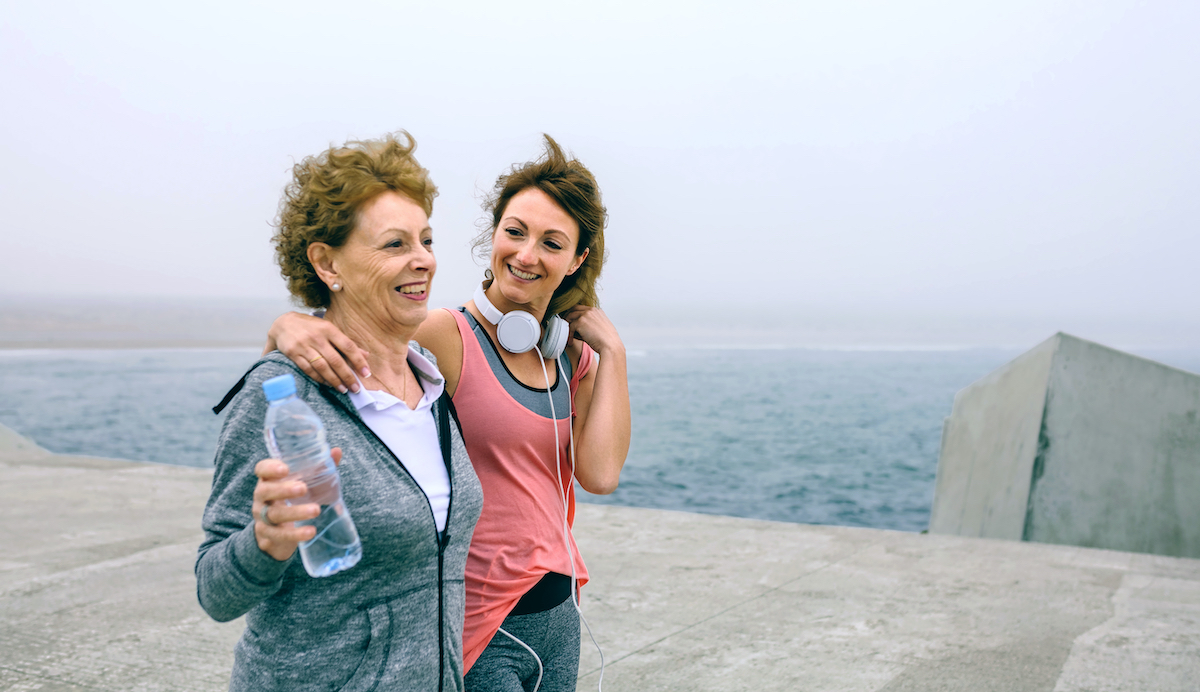 Senior woman and young woman walking outdoors along sea pier