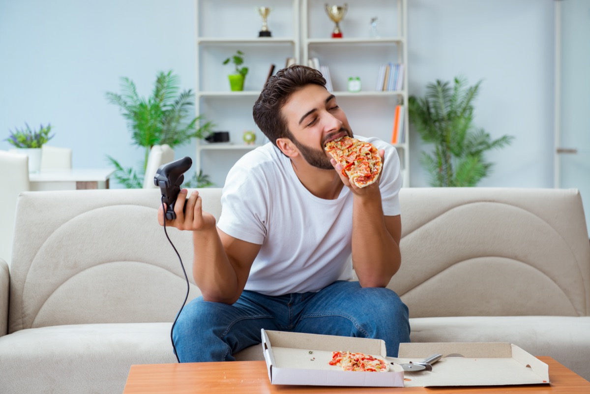 Hombre comiendo pizza con comida para llevar en casa descansando relajante