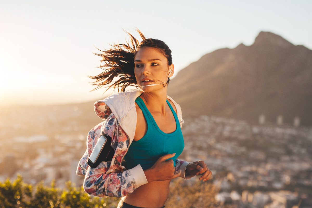 woman jogs at sunset on the hill overlooking the city