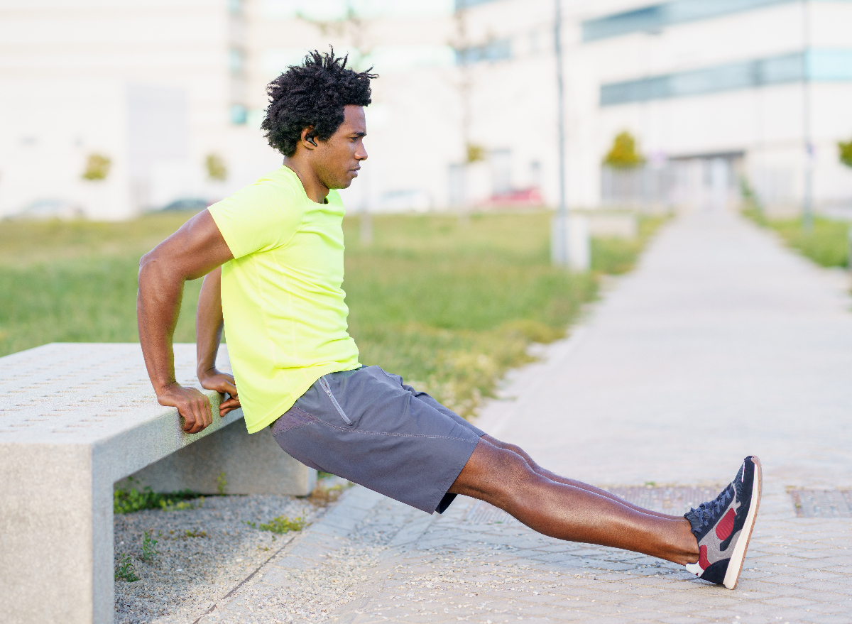 man performing bodyweight dip outside along walking path