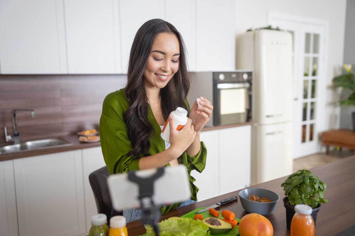 Smiling young lady looking at her vitamins