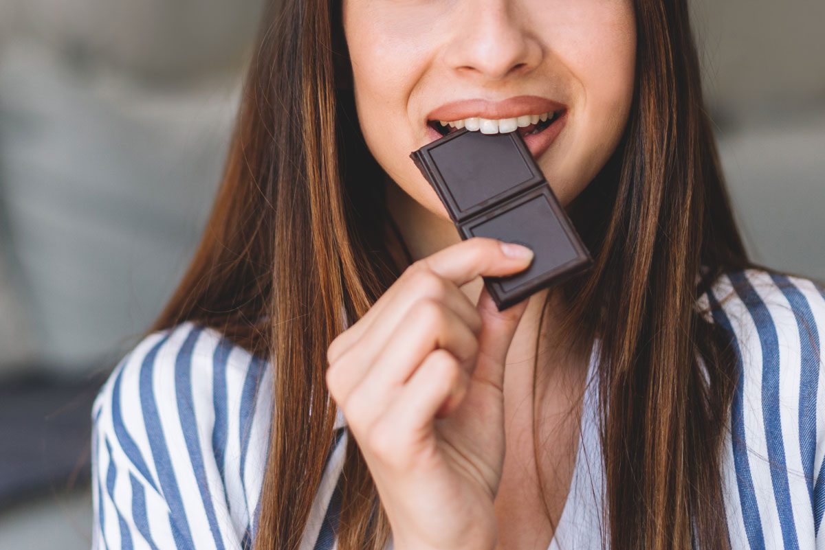 woman eating a bite of chocolate bar