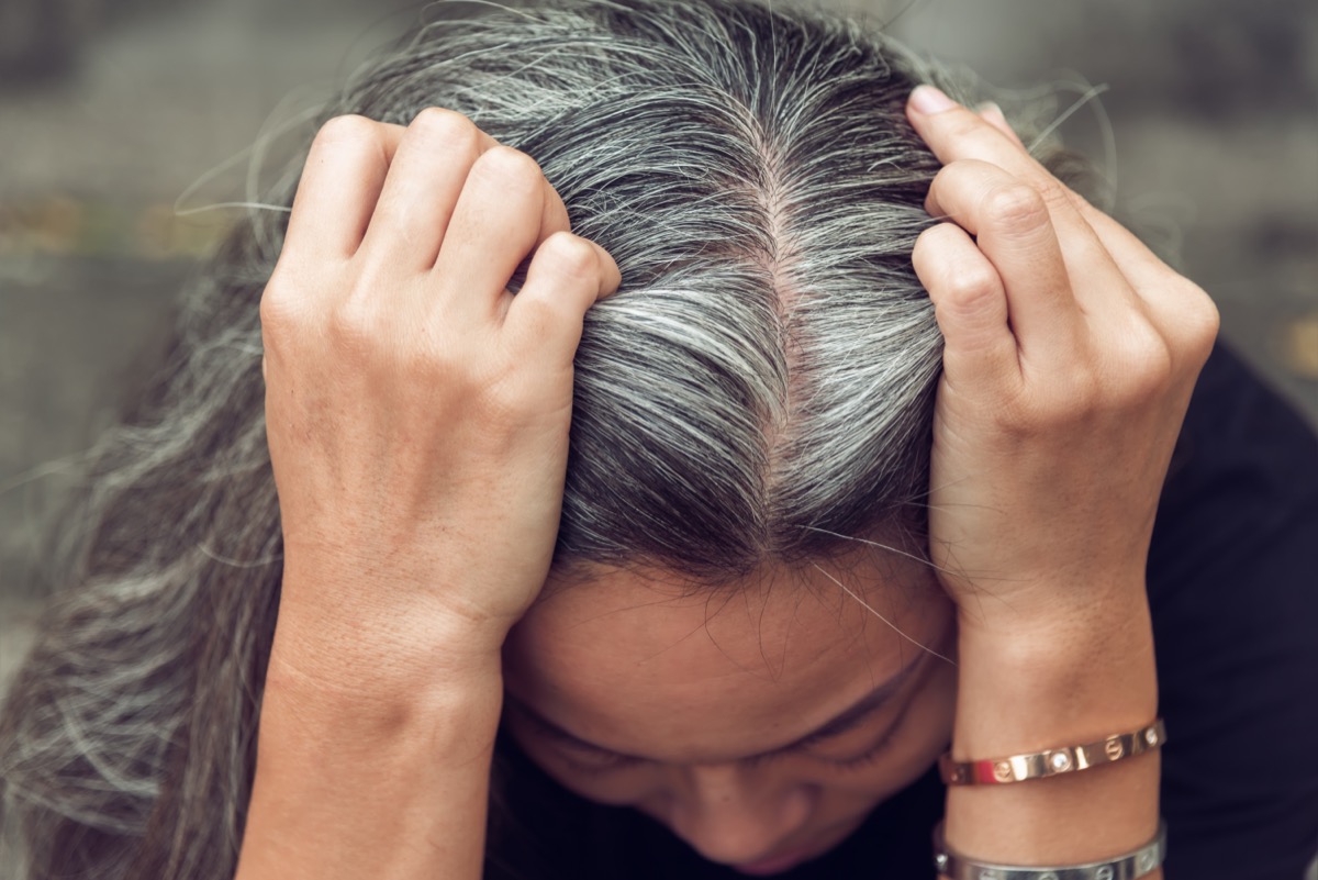 Close-up sad Asian woman showing her gray hair.