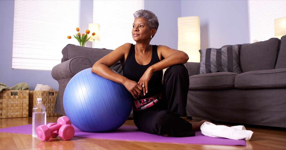 woman with gray hair trains with yoga ball at home