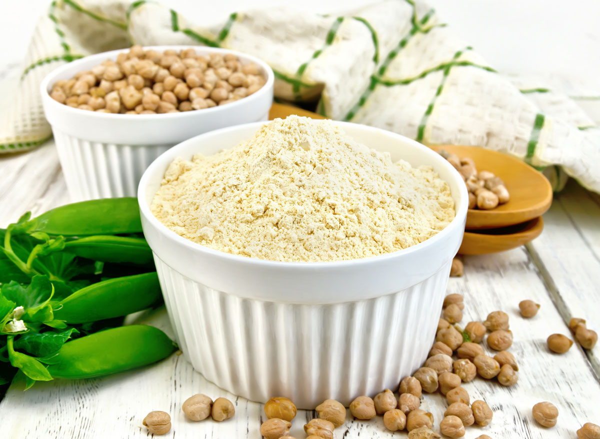 Vegan pea protein powder in white ramekin next to a whole pea pod