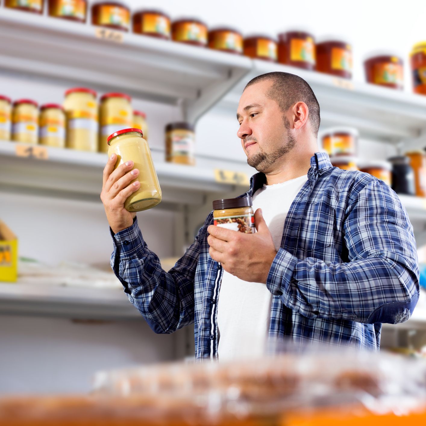 portrait of ordinary man buying peanut butter in supermarket