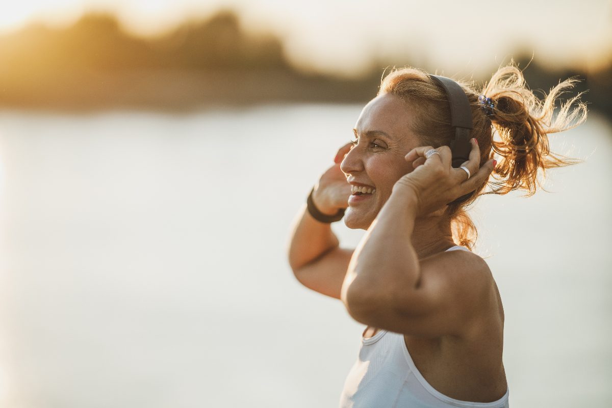 mujer feliz trotando en la playa en un día soleado