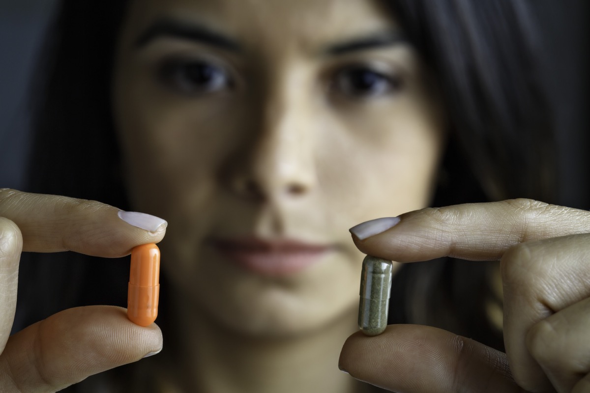 Hispanic young woman choosing between antibiotics or alternative medicine.