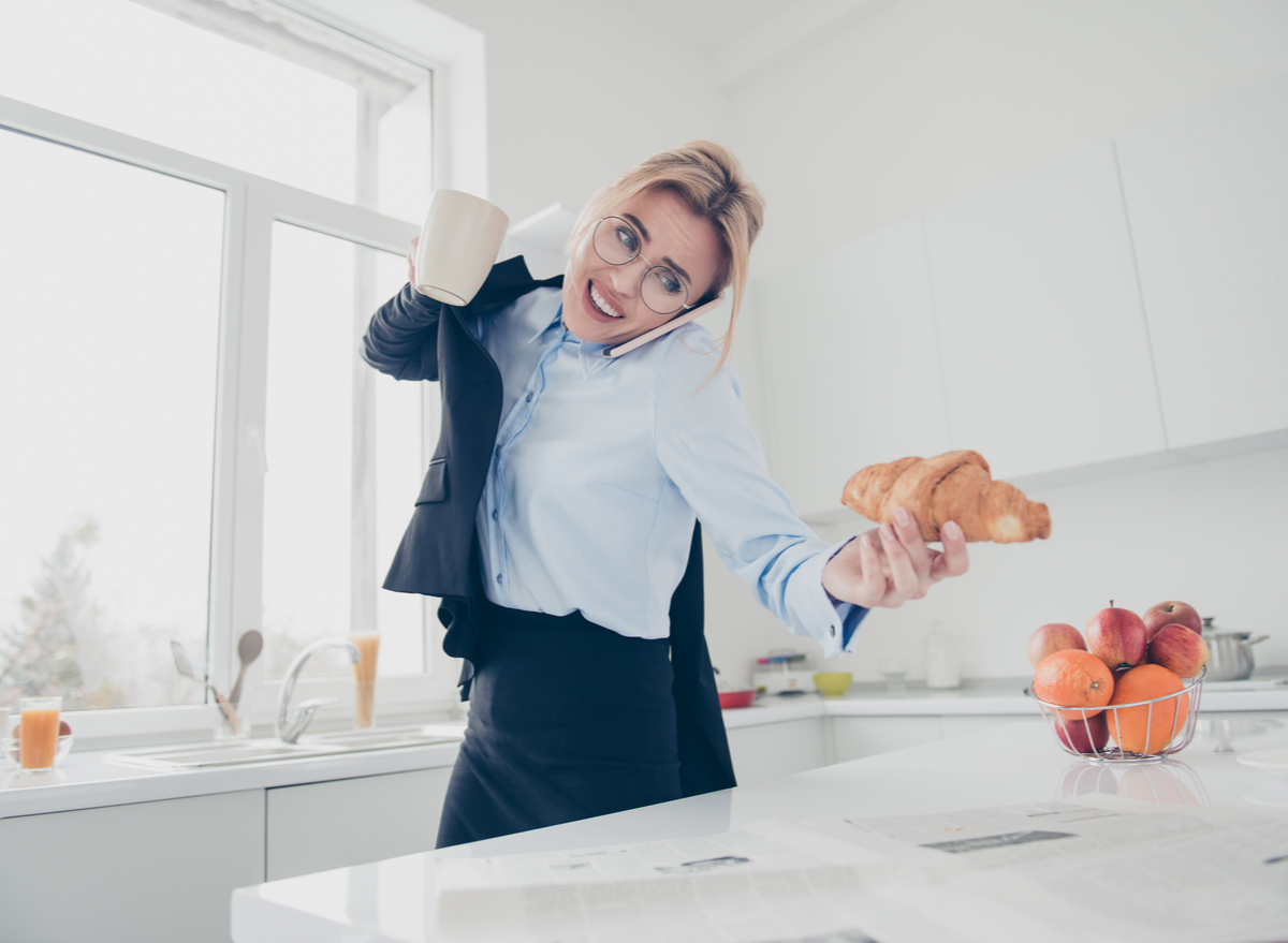 woman running, talking on the phone and holding a croissant