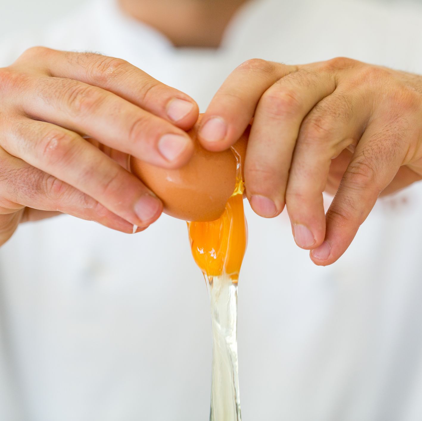 close-up of hand breaking egg